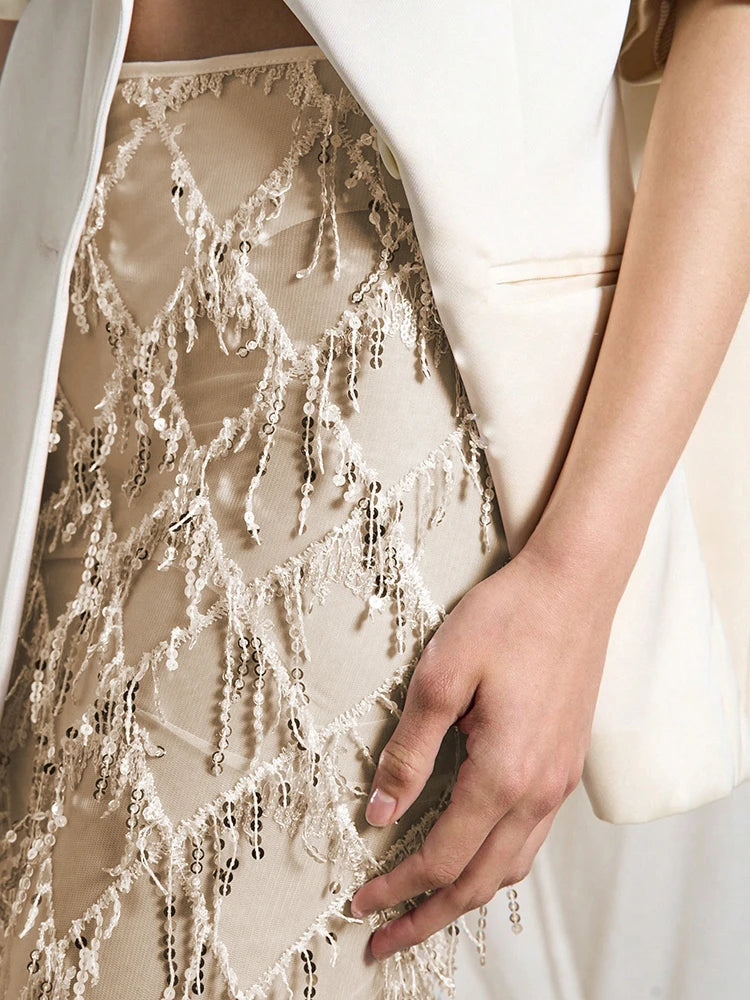 Close-up of a person wearing a beige lace dress with a white jacket.