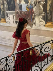 A woman posing in a flowing red dress with layered ruffles, accentuating the elegant silhouette.