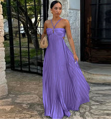 Woman in a purple dress standing outdoors near a stone wall.