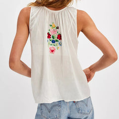 White sleeveless top with floral embroidery on the back, worn by a person against a white background.