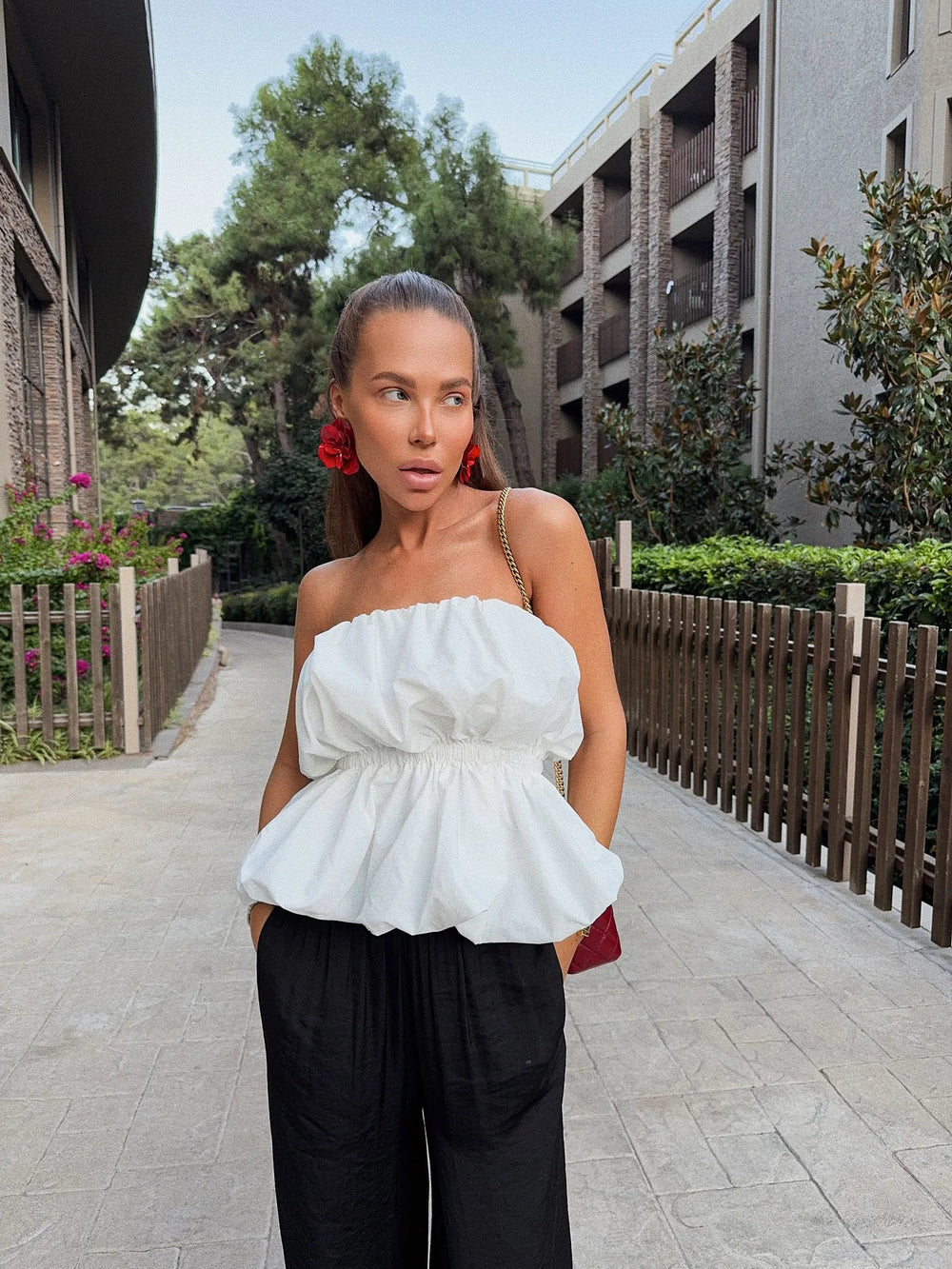 Woman wearing a white peplum top and black pants in an outdoor setting.