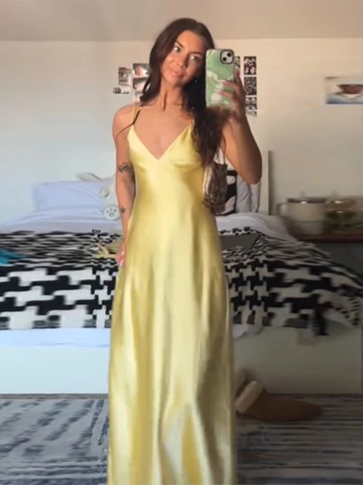 Woman wearing a yellow slip dress in a bedroom setting.