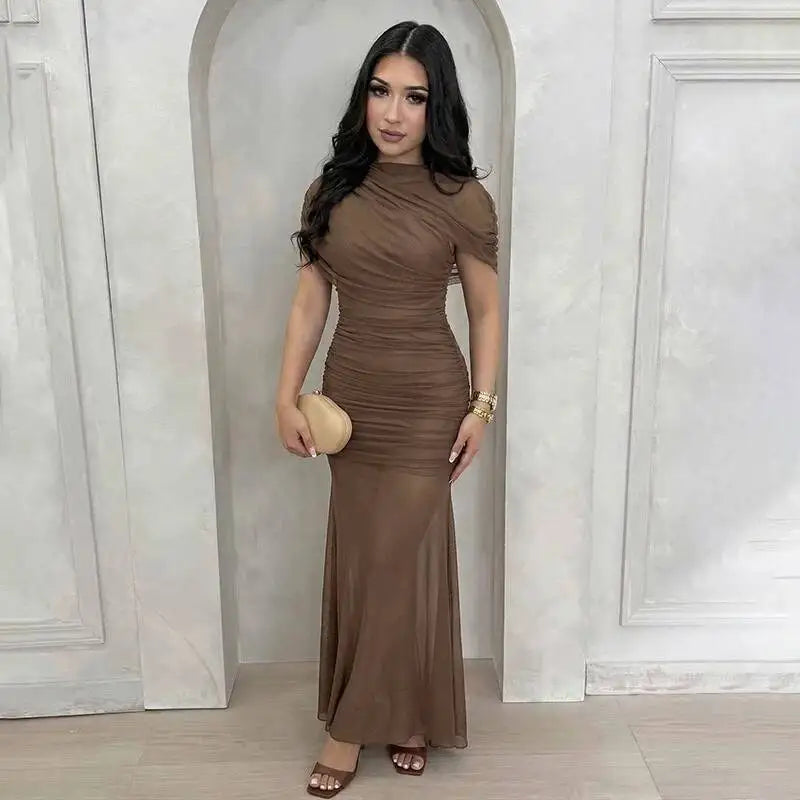 Woman in a brown dress standing in a decorative doorway.