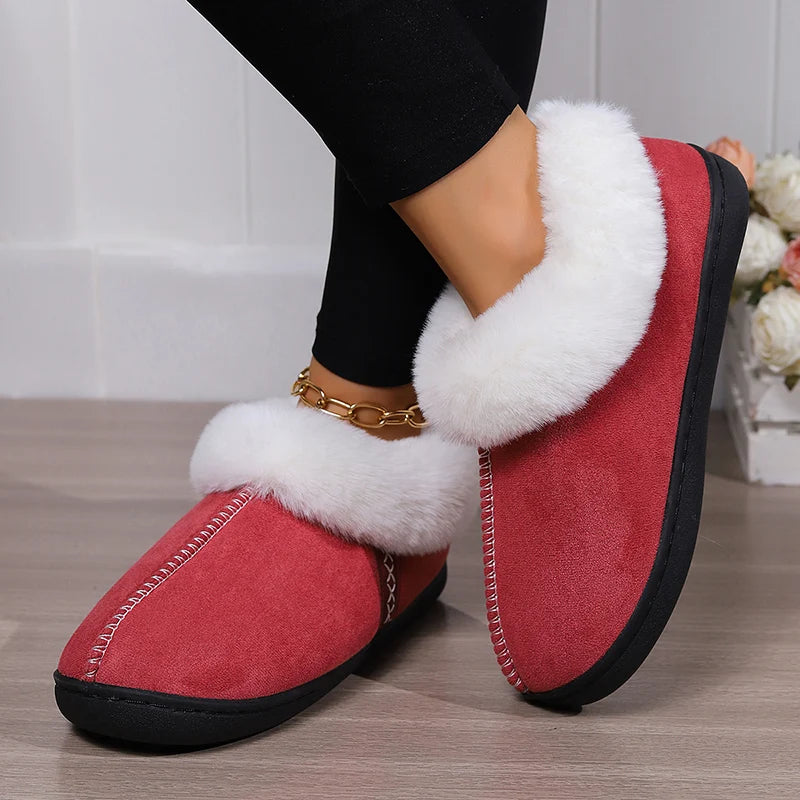 Red slippers with white fur trim worn indoors on a wooden floor.