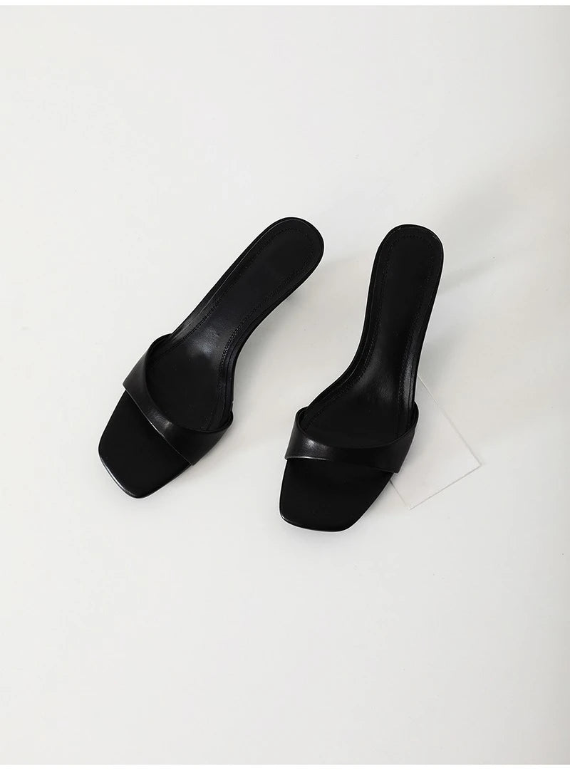 Pair of black high-heeled shoes on a light gray background