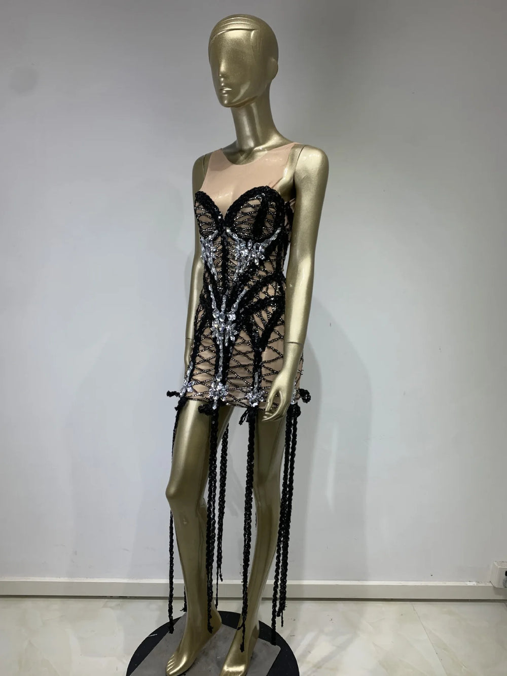 Mannequin wearing a black lace dress with silver embellishments on a plain background