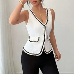 White sleeveless blazer with black trim worn by a person against a neutral background