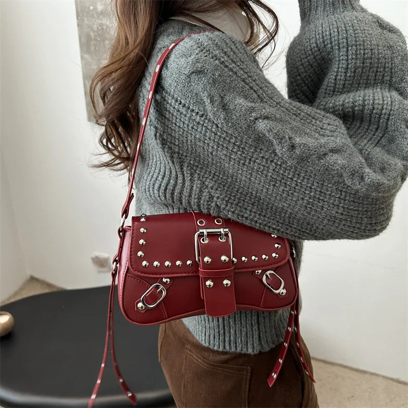 Person wearing a gray sweater with a red studded handbag.