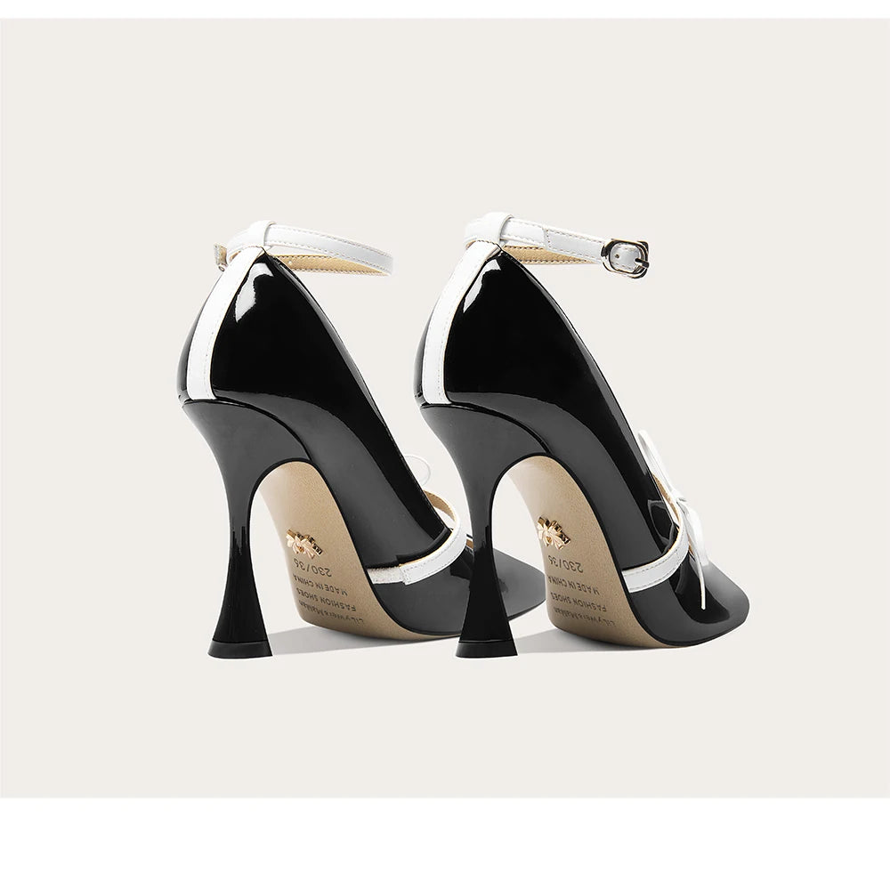 Black high-heeled shoes with white accents on a light gray background