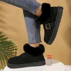 Black suede boots with fur trim worn by a person, on a beige background.