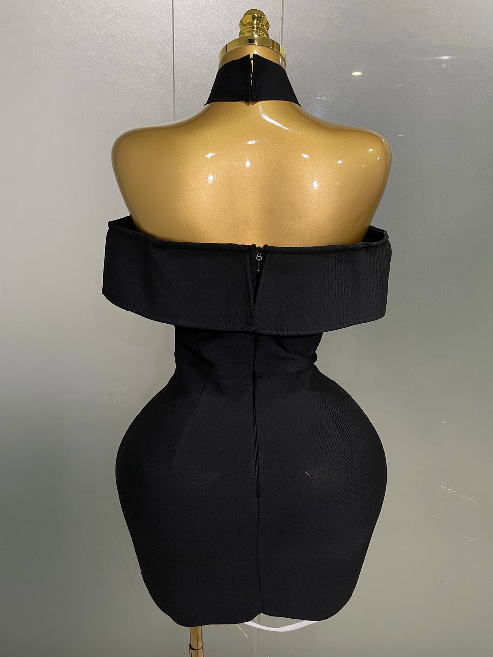 Black dress on a mannequin against a plain background