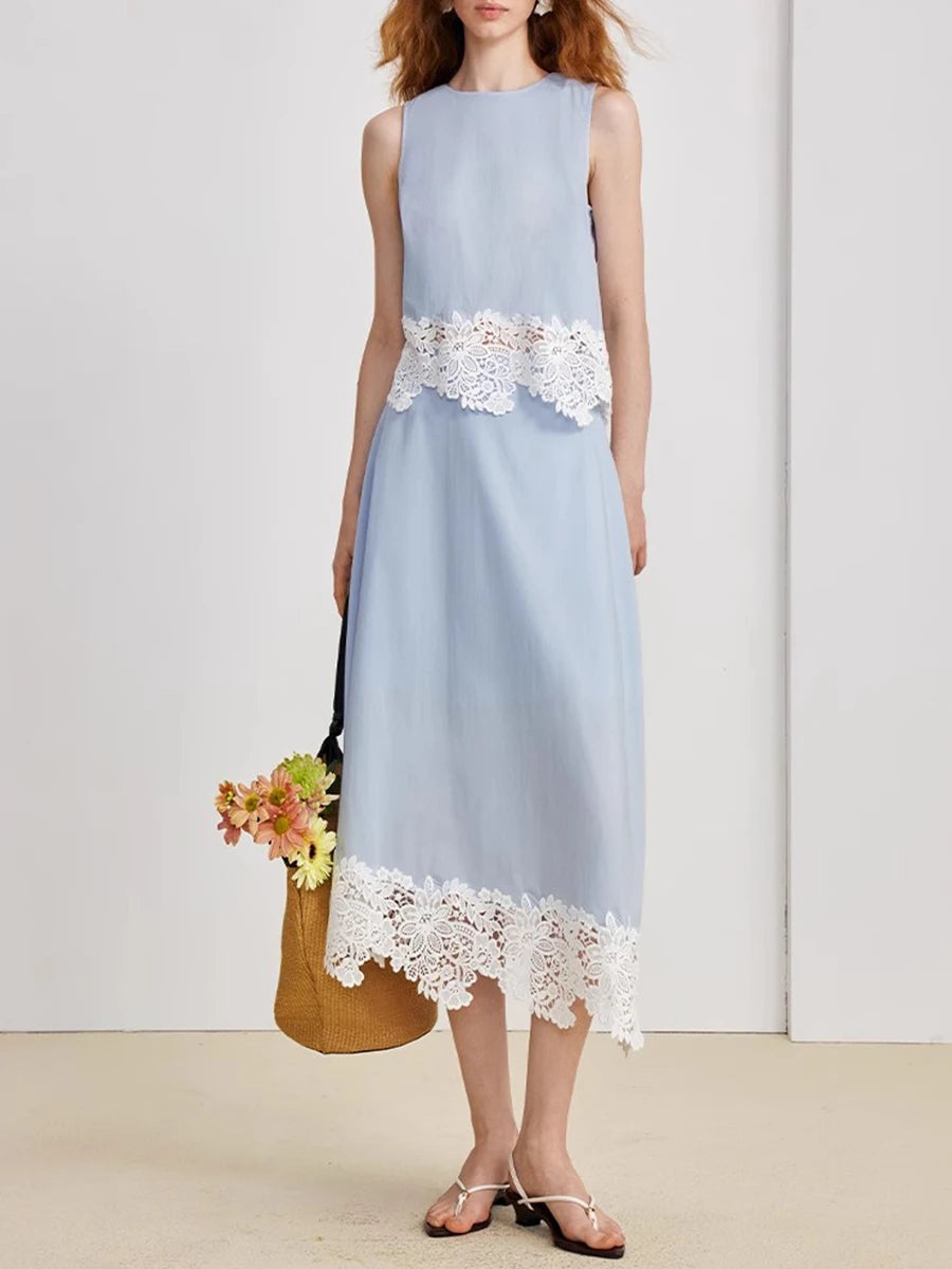 Light blue dress with white lace details worn by a person, standing against a plain background.