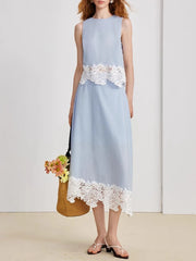 Light blue dress with white lace details worn by a person, standing against a plain background.
