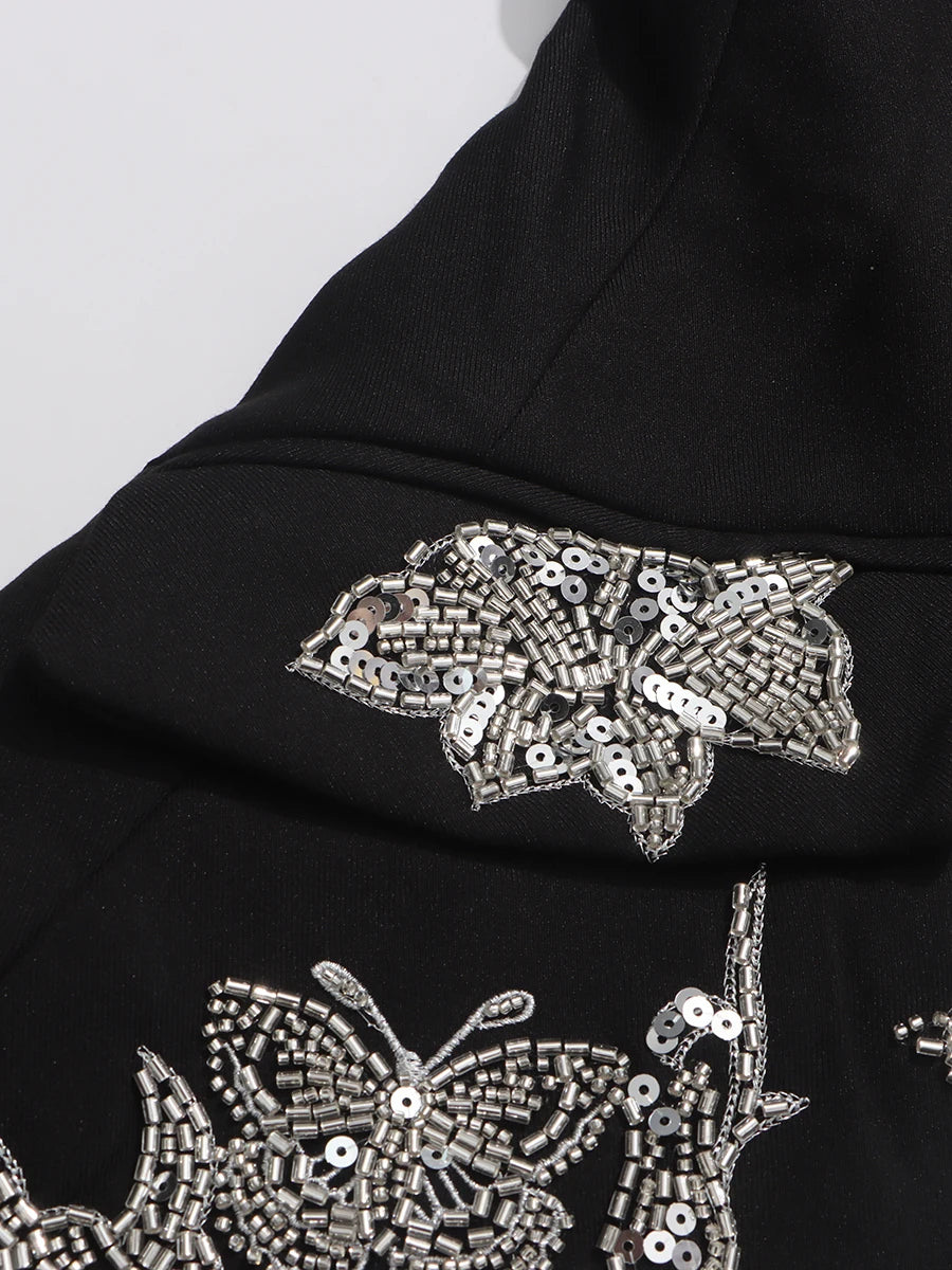 Black fabric with silver butterfly sequin embellishments on a white background
