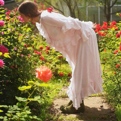 A woman in a pink dress standing in a garden with pink and red flowers