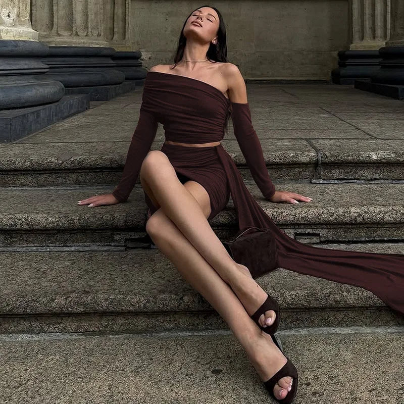 Woman in a brown dress sitting on stone steps with classical architecture in the background