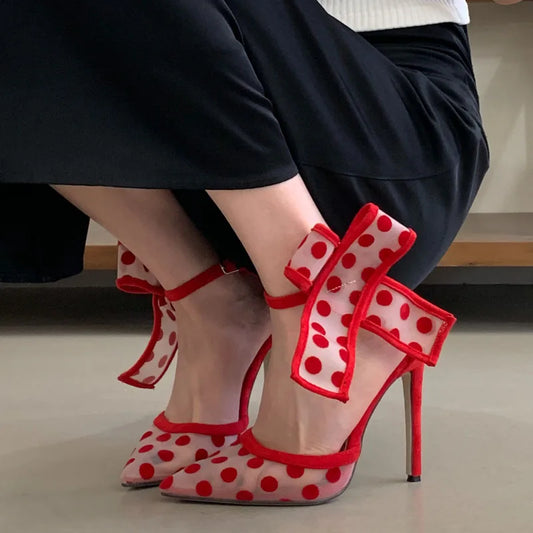 Close-up of polka dot mesh stiletto heels on a person's feet