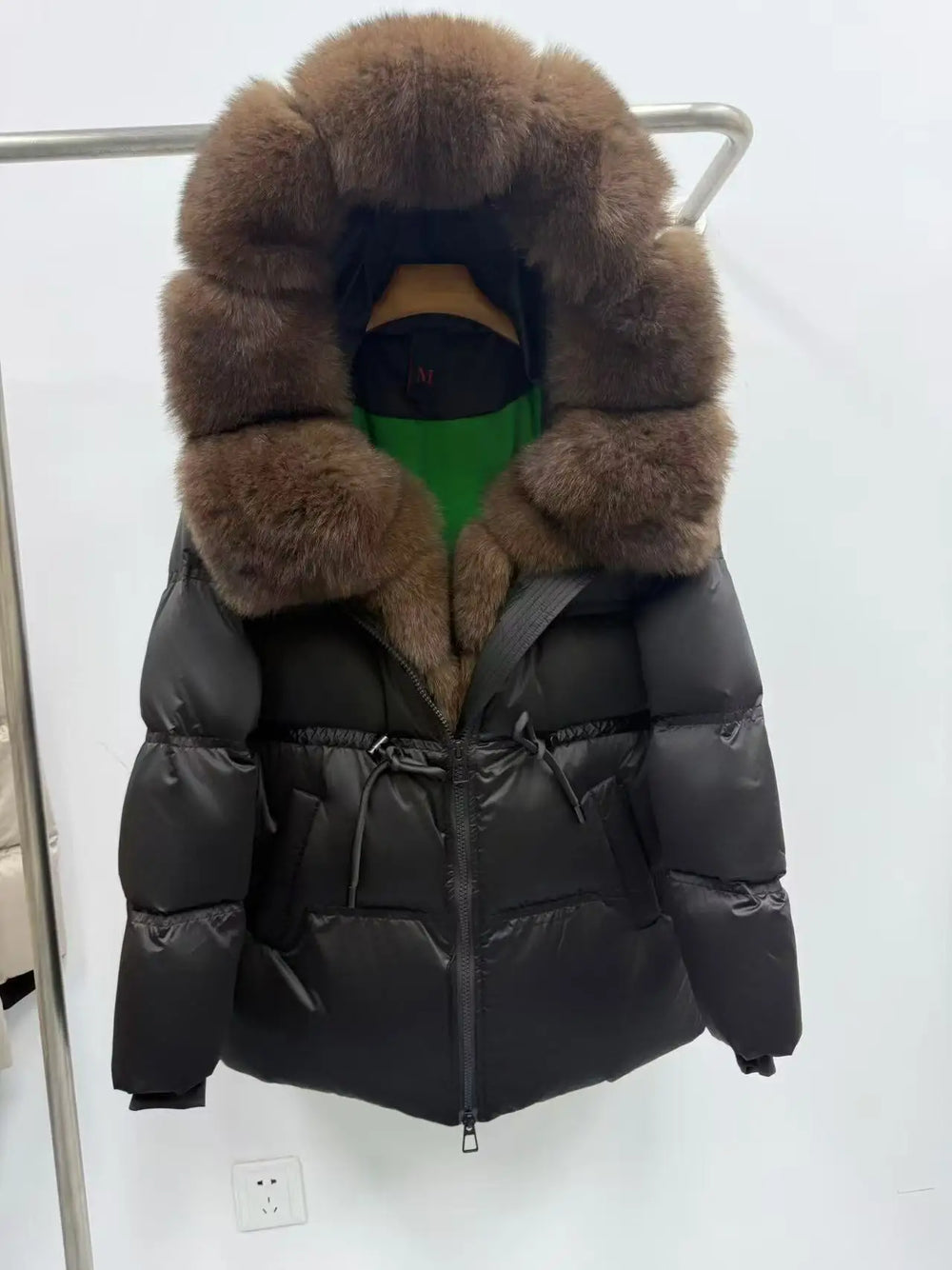 Black puffer jacket with large fur hood on a white background