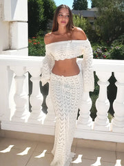 Woman wearing a white crochet outfit standing on a balcony with greenery in the background