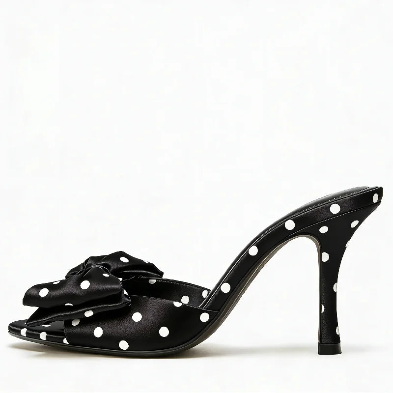Black high-heeled shoe with white polka dots on a white background
