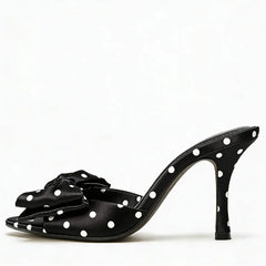 Black high-heeled shoe with white polka dots on a white background