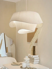 A modern designer fabric pendant light with a soft, warm glow hanging in a cozy bedroom. B