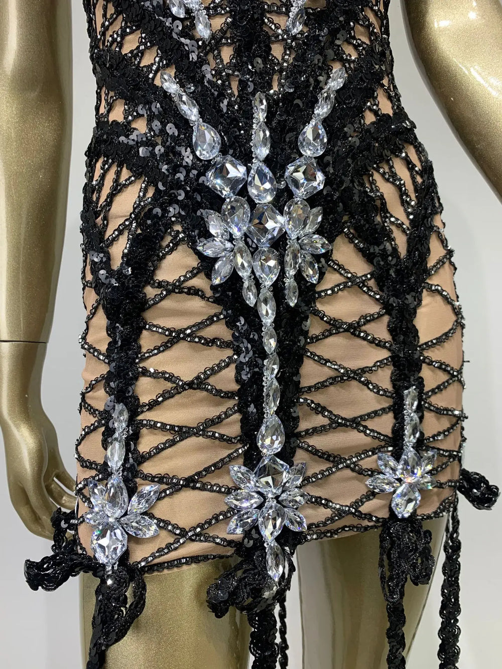 Black lace garment with floral embellishments on a mannequin.