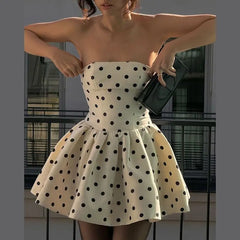 Woman wearing a strapless polka dot dress holding a clutch.