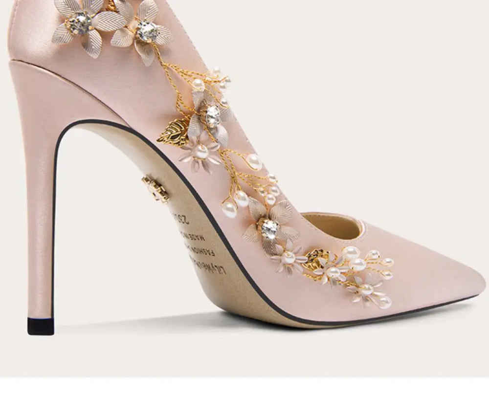 Pink high-heeled shoe with floral embellishments on a white background