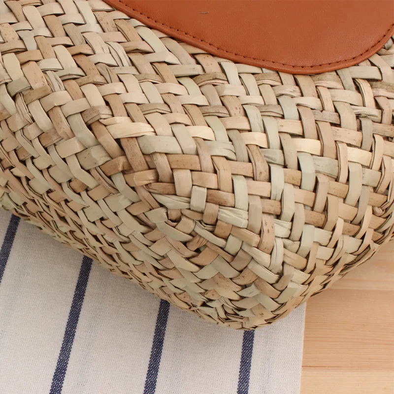 Close-up of a woven basket with a brown leather patch on a striped fabric background