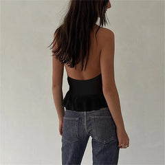 Person wearing a black peplum top and blue jeans against a plain background