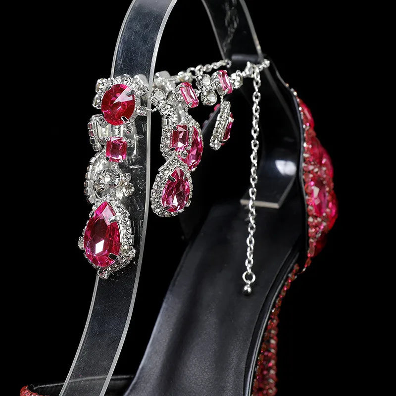 Black high-heeled shoe with red gemstone embellishments on a black background