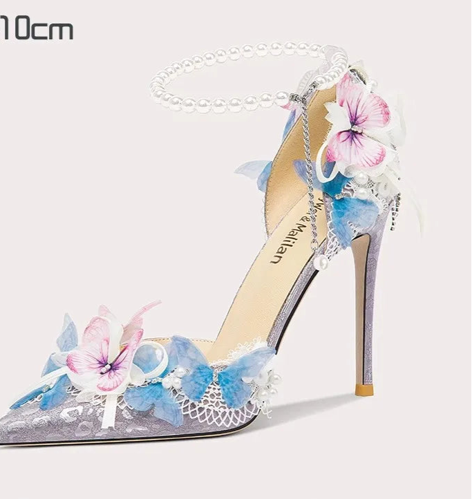 High-heeled shoe with floral design and pearl chain on a white background