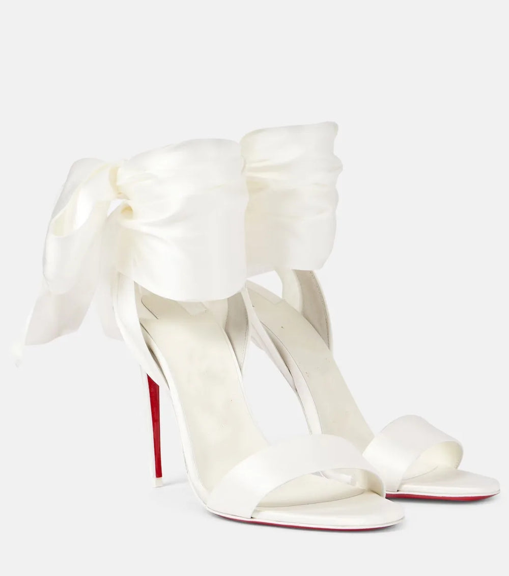 Pair of white satin stiletto heels with large bow ankle straps
