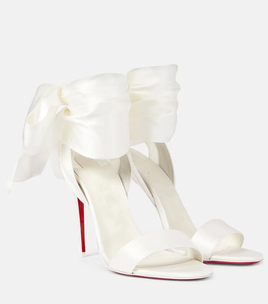 Pair of white satin stiletto heels with large bow ankle straps