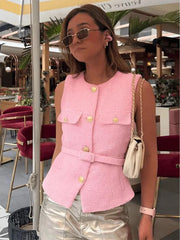 Woman wearing a pink vest with gold buttons in an outdoor setting.