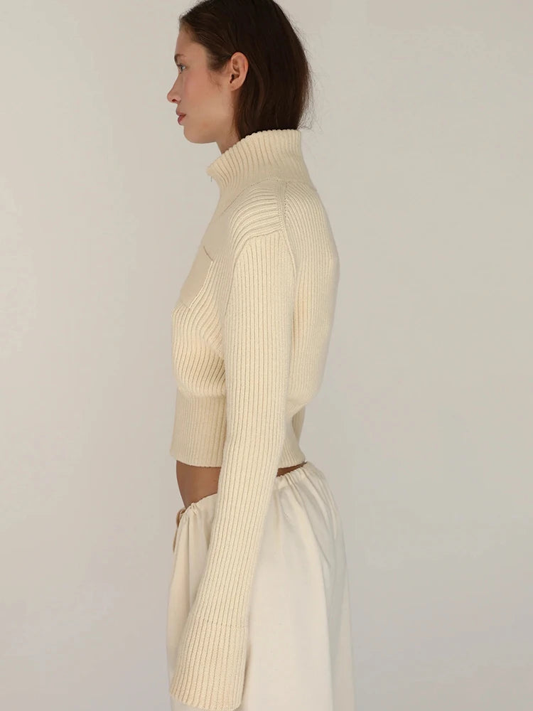 Woman wearing a cream ribbed knit top and skirt set against a plain background