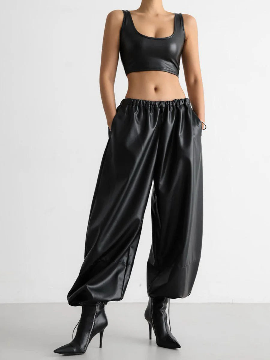 Person wearing a black leather outfit with high-waisted pants and a crop top on a white background