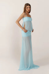 Woman wearing a light blue dress with a sheer overlay on a white background