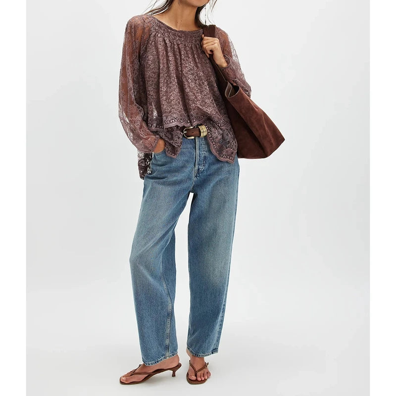 Person wearing a patterned top and blue jeans, holding a brown bag on a white background