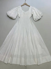 White dress with puff sleeves on a hanger against a gray background