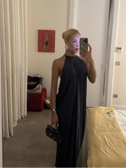 Person wearing a black dress taking a mirror selfie in a room.