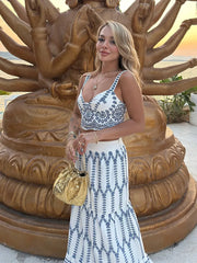 Woman in a patterned dress standing in front of a large golden statue.