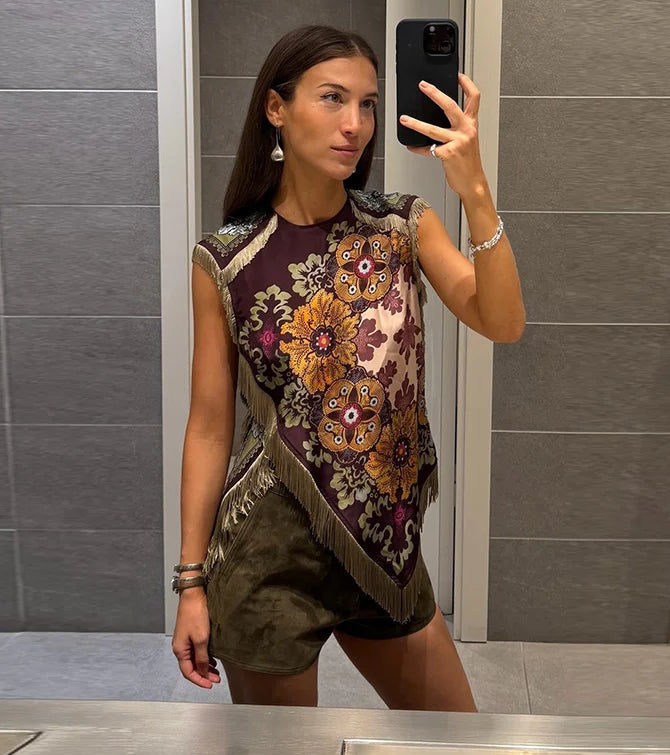 Woman taking a mirror selfie wearing a patterned top and shorts in a bathroom.