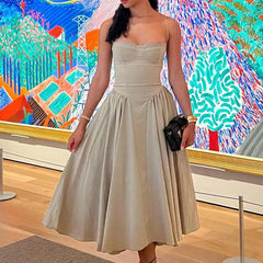 Woman in a beige dress standing in front of colorful abstract art