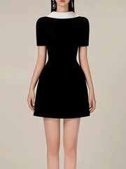 Black dress with white collar on a neutral background