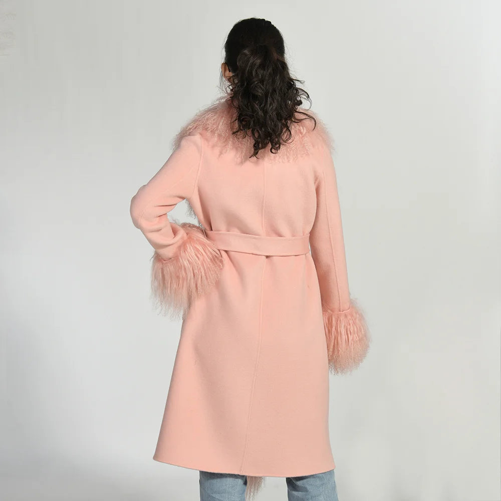 Person wearing a light pink coat with feather details on a plain background