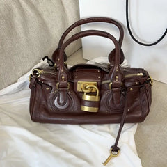 burgundy metallic lock satchel handbag with gold hardware,
