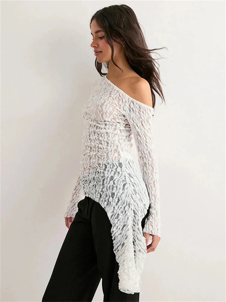 Woman wearing a white lace off-shoulder top against a plain background