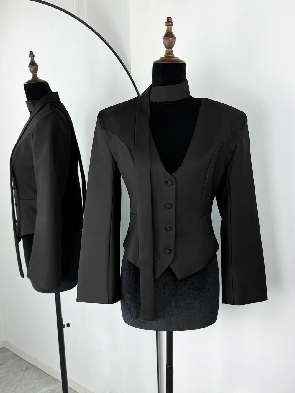 Black suit jacket and waistcoat on mannequins against a white background